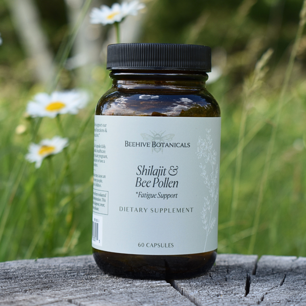 Supplement bottle labeled 'Shilajit & Bee Pollen' by Beehive Botanicals on a wooden surface with a natural background.