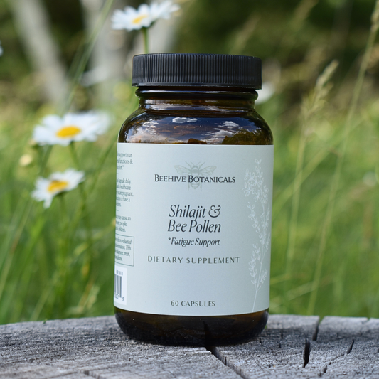 Supplement bottle labeled 'Shilajit & Bee Pollen' by Beehive Botanicals on a wooden surface with a natural background.